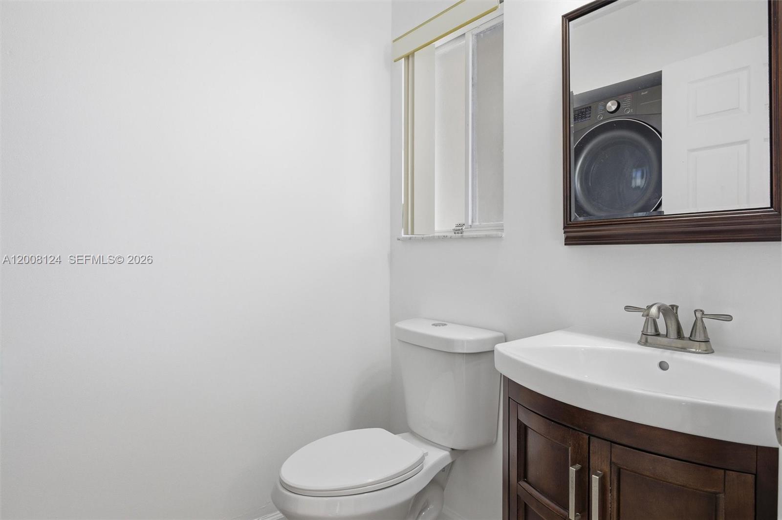 A bathroom features a white toilet, a dark wood vanity with a sink, and a mirror — 17530 SW 139th Ct, Miami FL 33177, MIAMI, FL