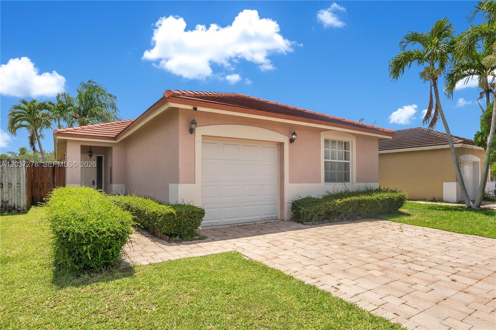 A single-story peach-colored house with a tiled roof, a garage, and a paved driveway — 14530 SW 156th Ave, Miami FL 33196, MIAMI, FL