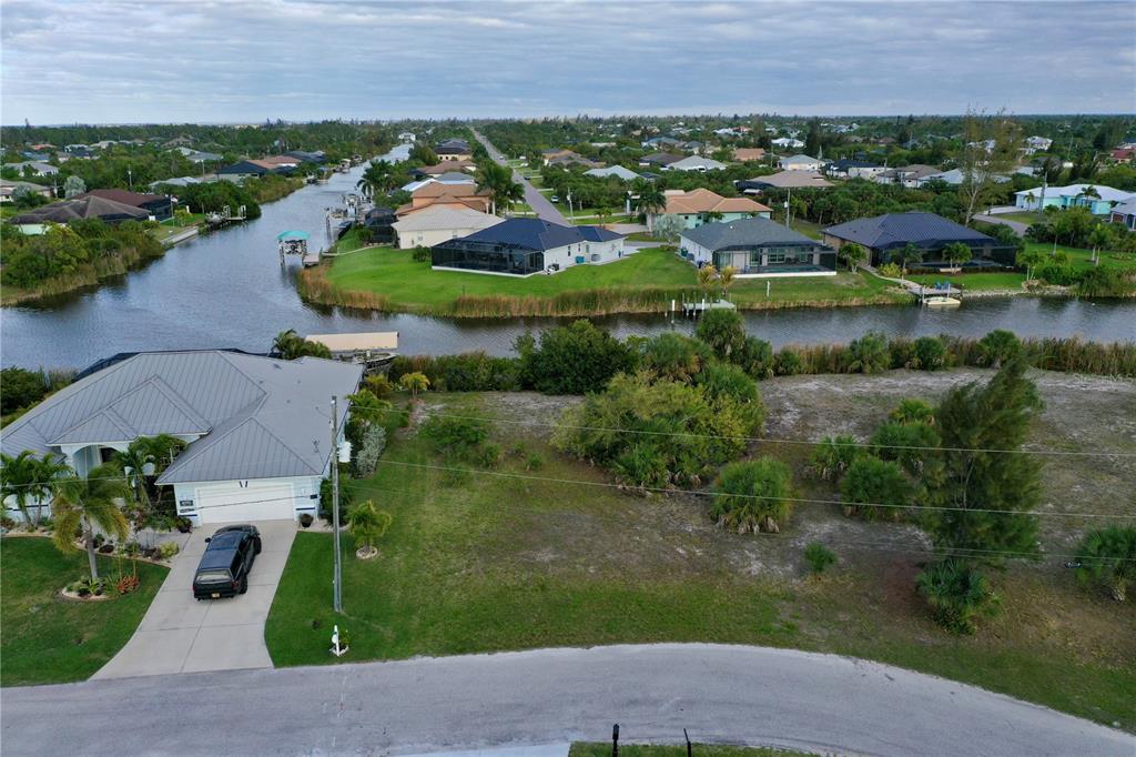 An aerial view shows a vacant residential lot next to a house and a canal — 14702 LILLIAN CIRCLE, PORT CHARLOTTE, FL