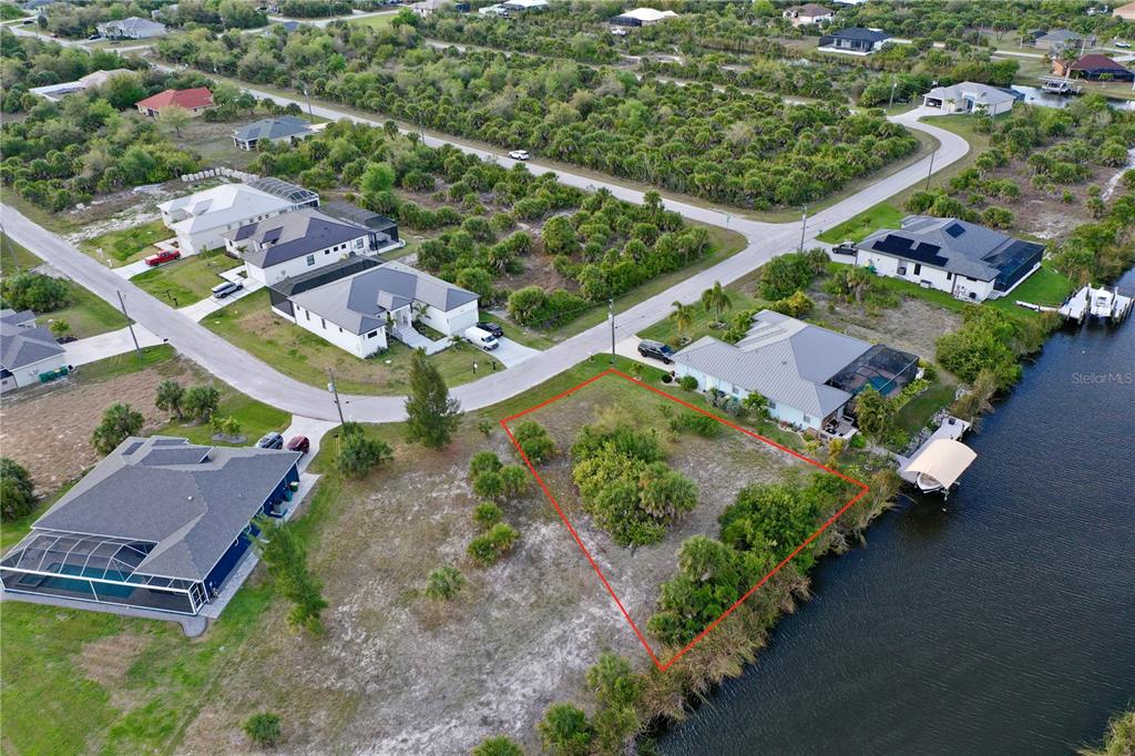 An aerial view shows a vacant waterfront lot outlined in red within a residential neighborhood — 14702 LILLIAN CIRCLE, PORT CHARLOTTE, FL