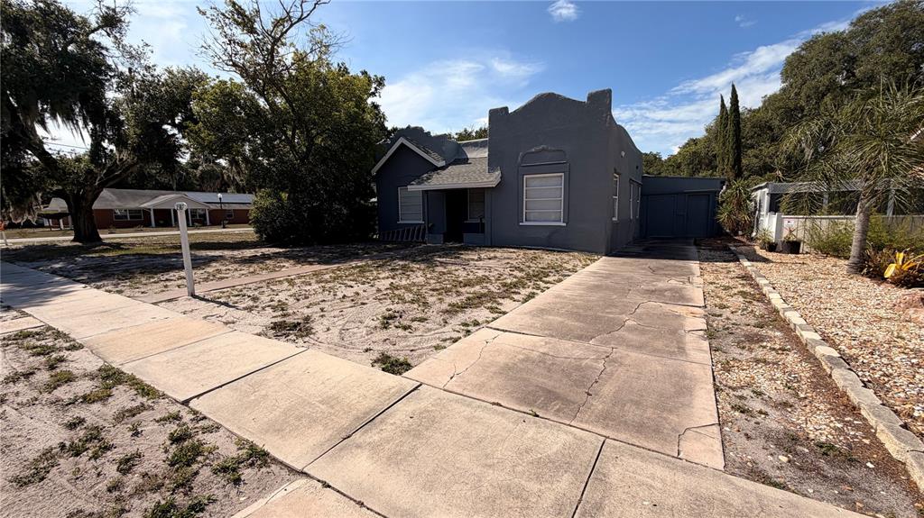A gray, single-story house with a flat roofline and a concrete driveway sits on a lot — 2387 SHERIDAN ROAD, MOUNT DORA, FL