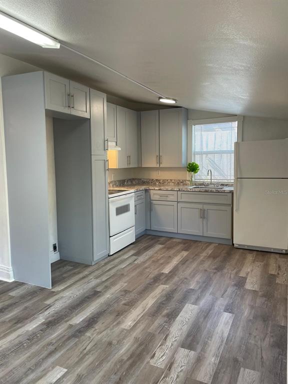 A kitchen features light gray cabinets, white appliances, laminate countertops, and wood-look flooring — 2387 SHERIDAN ROAD, MOUNT DORA, FL