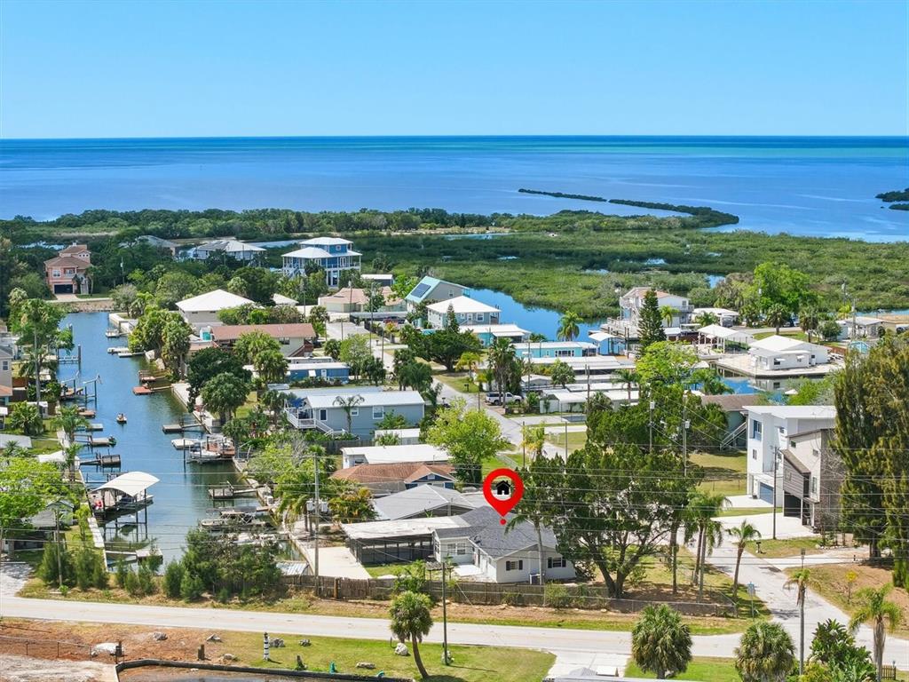 An aerial view shows a house with a red location pin near a canal — 7114 FAIR LANE, HUDSON, FL