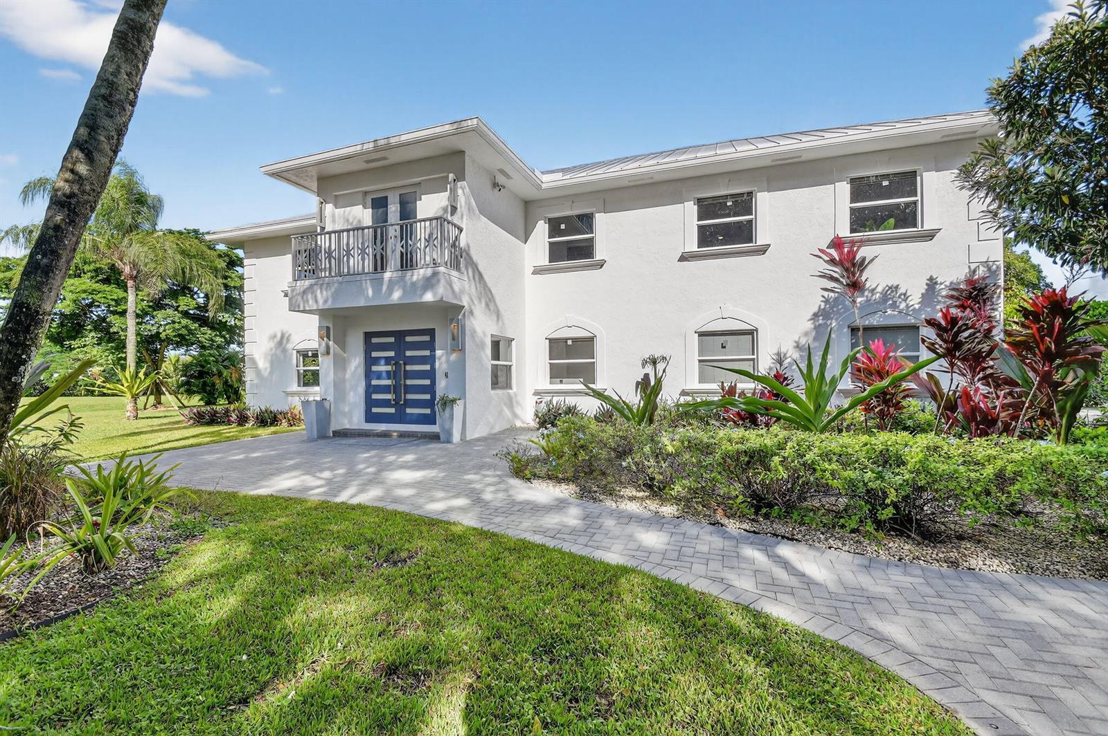 A two-story white house with a blue front door and a balcony under a clear sky — 2900 Greenbriar Boulevard, Wellington FL 33414, WELLINGTON, FL
