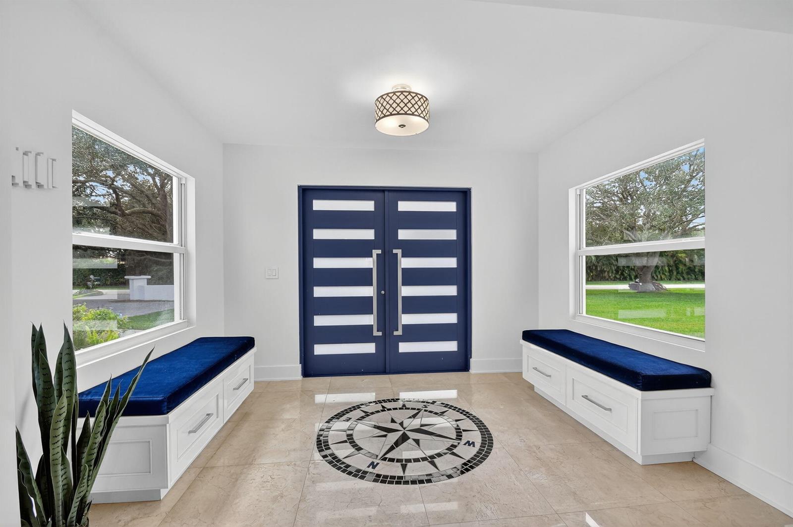A bright entryway features a blue double door, two built-in benches, and a compass floor inlay — 2900 Greenbriar Boulevard, Wellington FL 33414, WELLINGTON, FL
