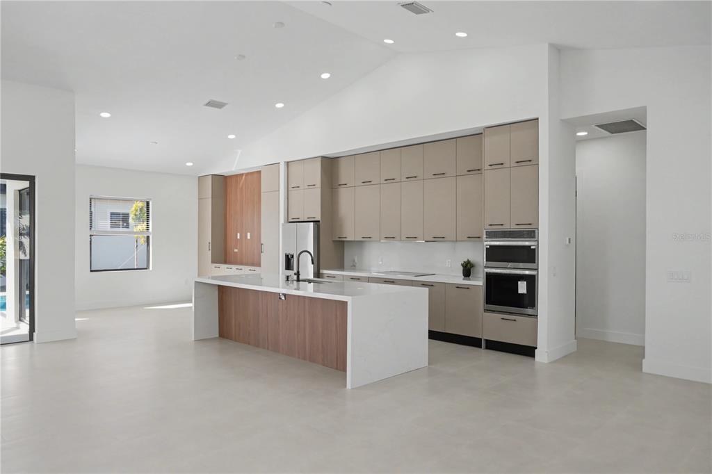 A modern kitchen features a white quartz island, two-tone cabinetry, and stainless steel appliances — 14687 LILLIAN CIRCLE, PORT CHARLOTTE, FL
