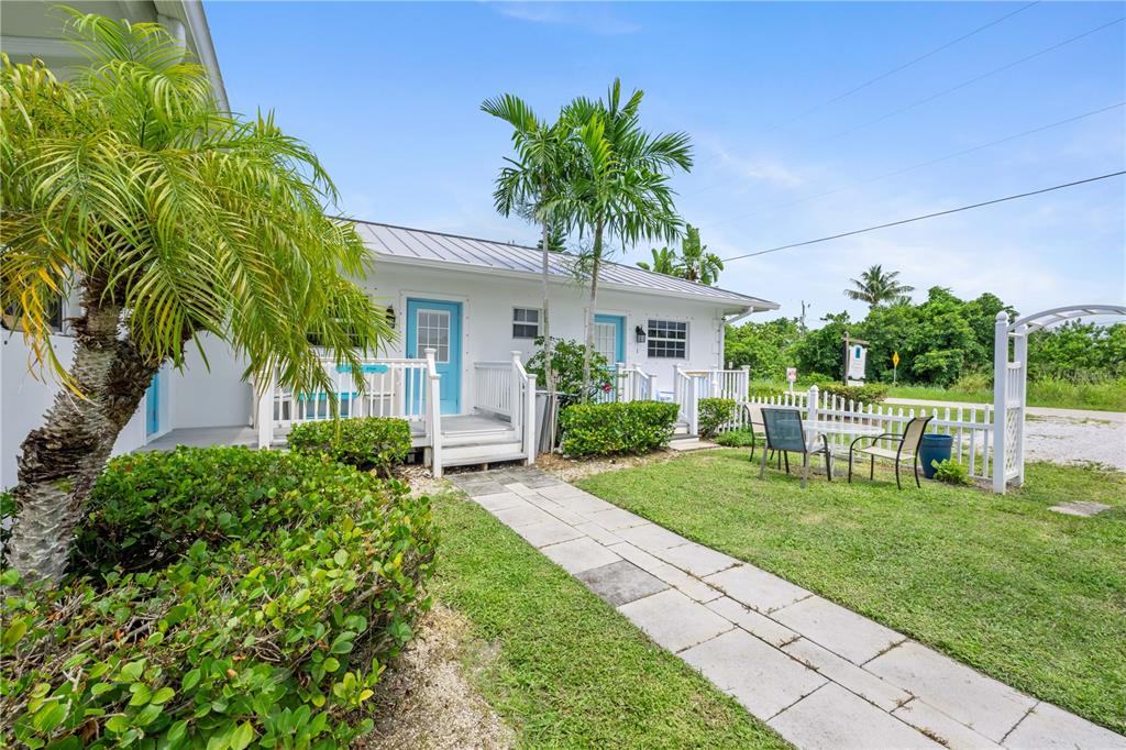 A white single-story building with blue doors, a palm tree, and a stone walkway — 2502 TAMARIND DRIVE, FORT PIERCE, FL