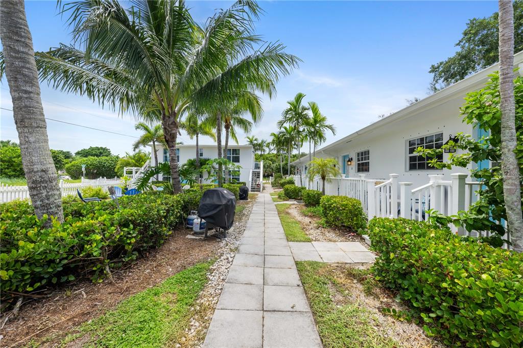 A paved walkway leads between two white buildings surrounded by palm trees and landscaping — 2502 TAMARIND DRIVE, FORT PIERCE, FL