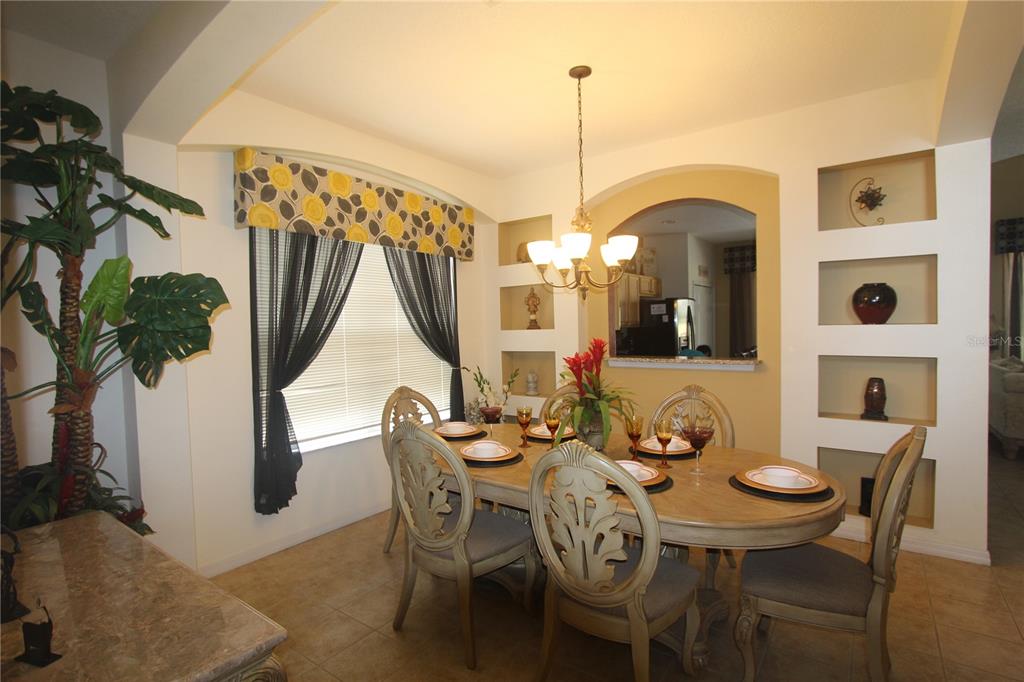A dining room features a wooden table, six chairs, arched wall niches, and a chandelier — 8475 OASIS KEY COVE, KISSIMMEE, FL