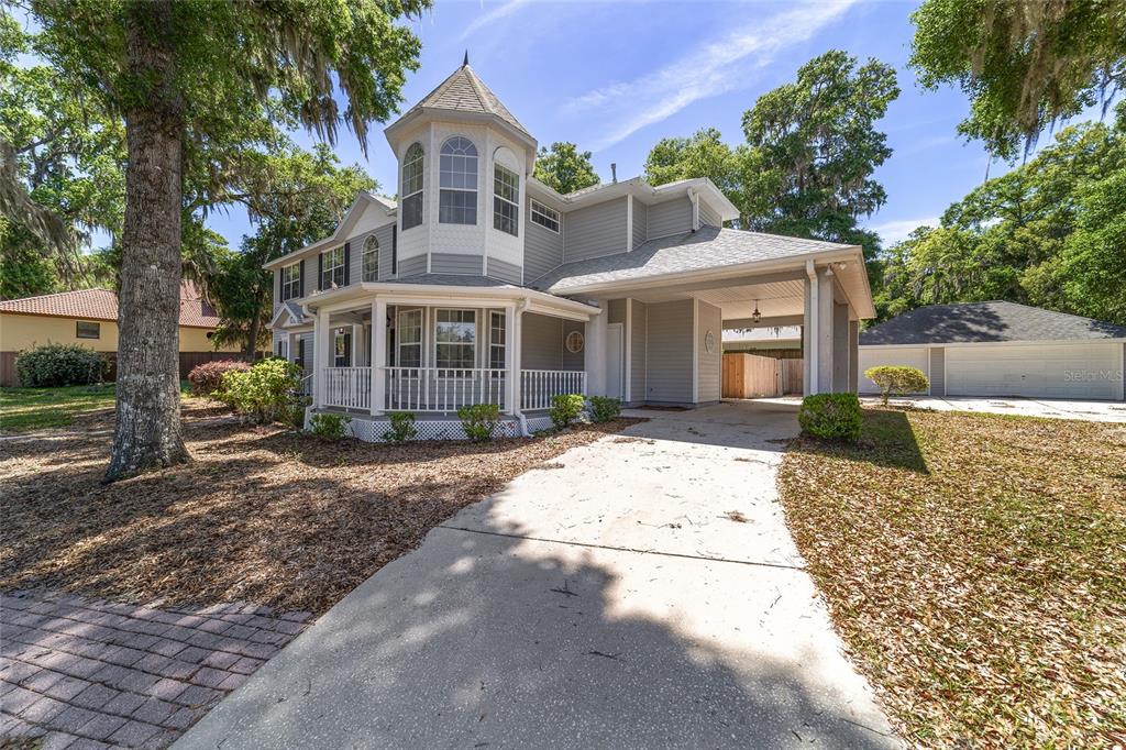 A two-story gray house with a turret, a wrap-around porch, and a detached garage — 1628 SE 29TH TERRACE, OCALA, FL