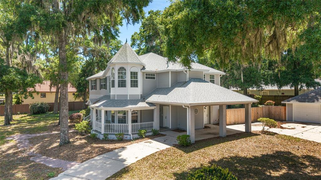 A two-story gray house with a turret, a wraparound porch, and a detached garage — 1628 SE 29TH TERRACE, OCALA, FL