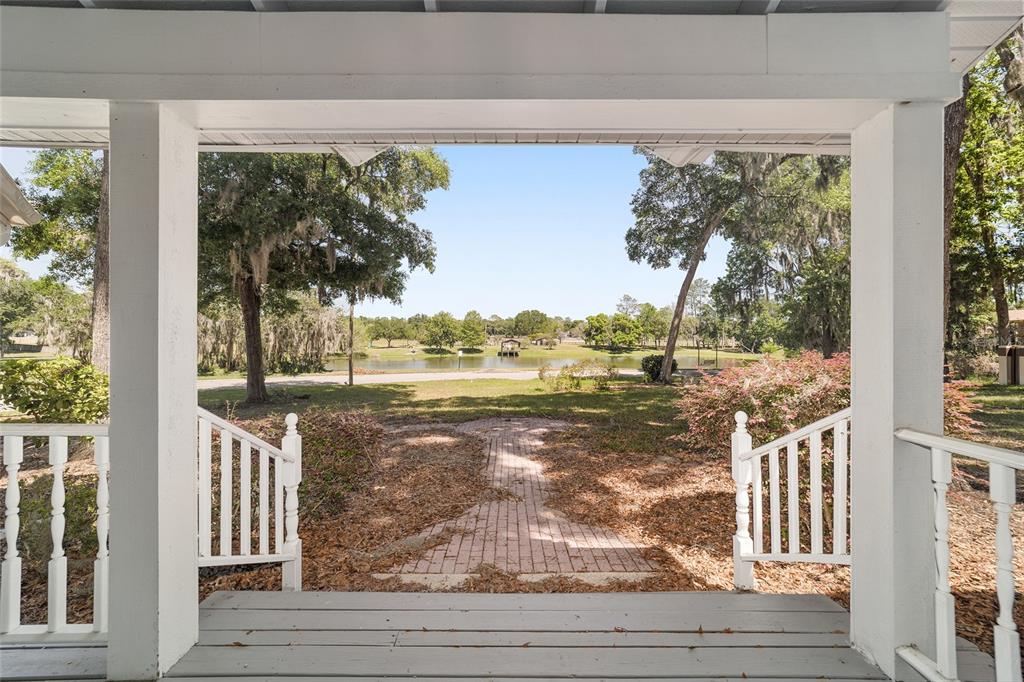 A view from a covered porch looking out toward a lake and trees — 1628 SE 29TH TERRACE, OCALA, FL