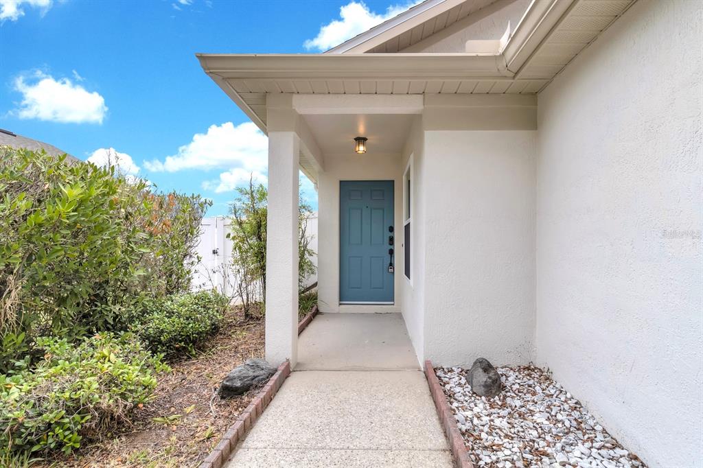 A concrete walkway leads to a blue front door under a covered porch — 8141 FORT THOMAS WAY, ORLANDO, FL