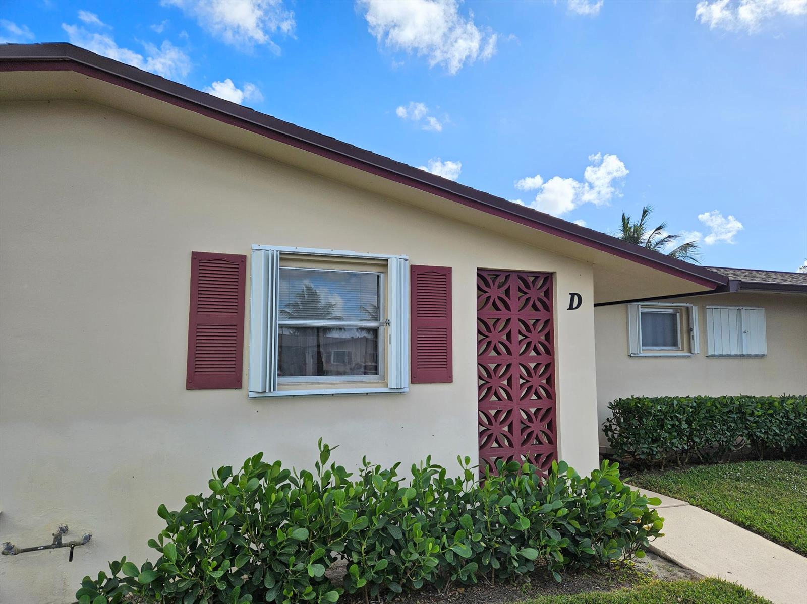 The exterior of a beige single-story building features a decorative screen door and red shutters — 2950 Crosley Drive E # D, West Palm Beach FL 33415, WEST PALM BEACH, FL