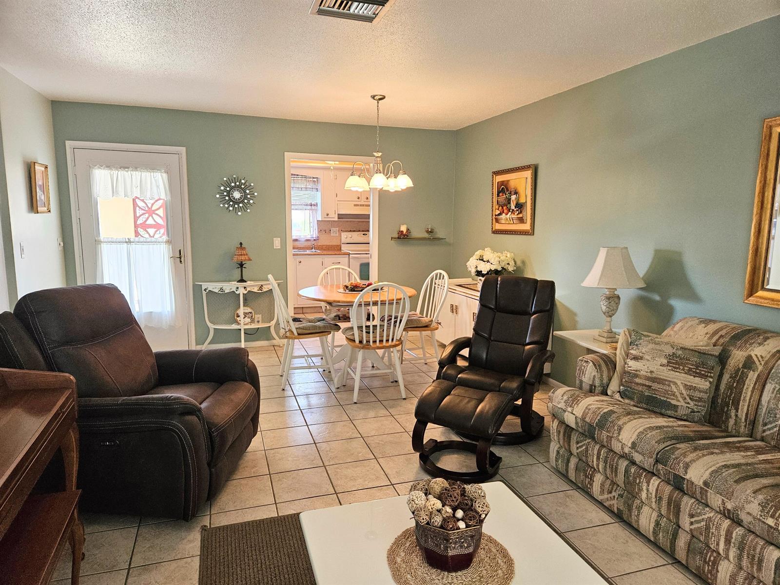 A living room with light green walls, tile flooring, a dining area, and comfortable seating — 2950 Crosley Drive E # D, West Palm Beach FL 33415, WEST PALM BEACH, FL