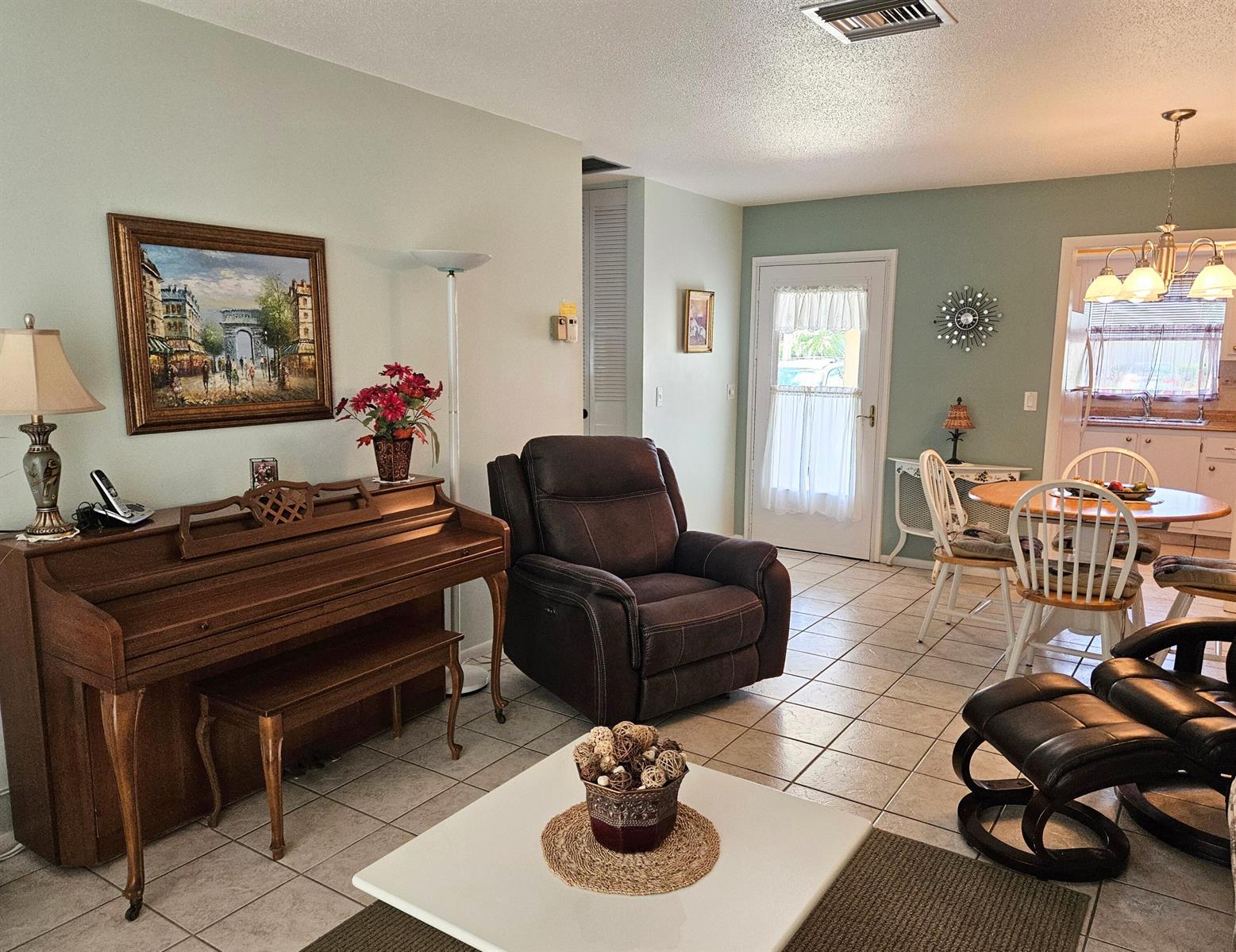 A living room with a piano, recliner, and dining area featuring tile floors and light walls — 2950 Crosley Drive E # D, West Palm Beach FL 33415, WEST PALM BEACH, FL