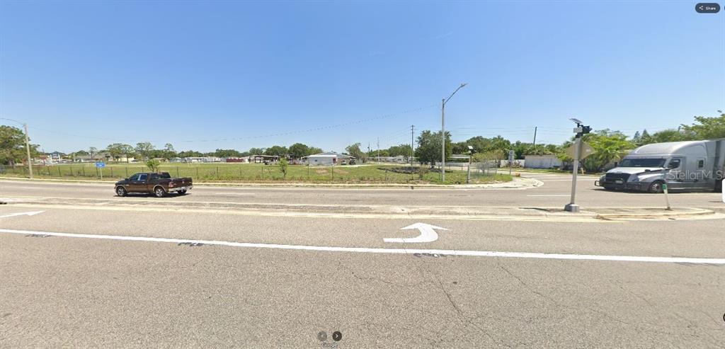 This exterior view shows a vacant, grassy lot bordered by a road and a fence — HWY 60 E, LAKE WALES, FL