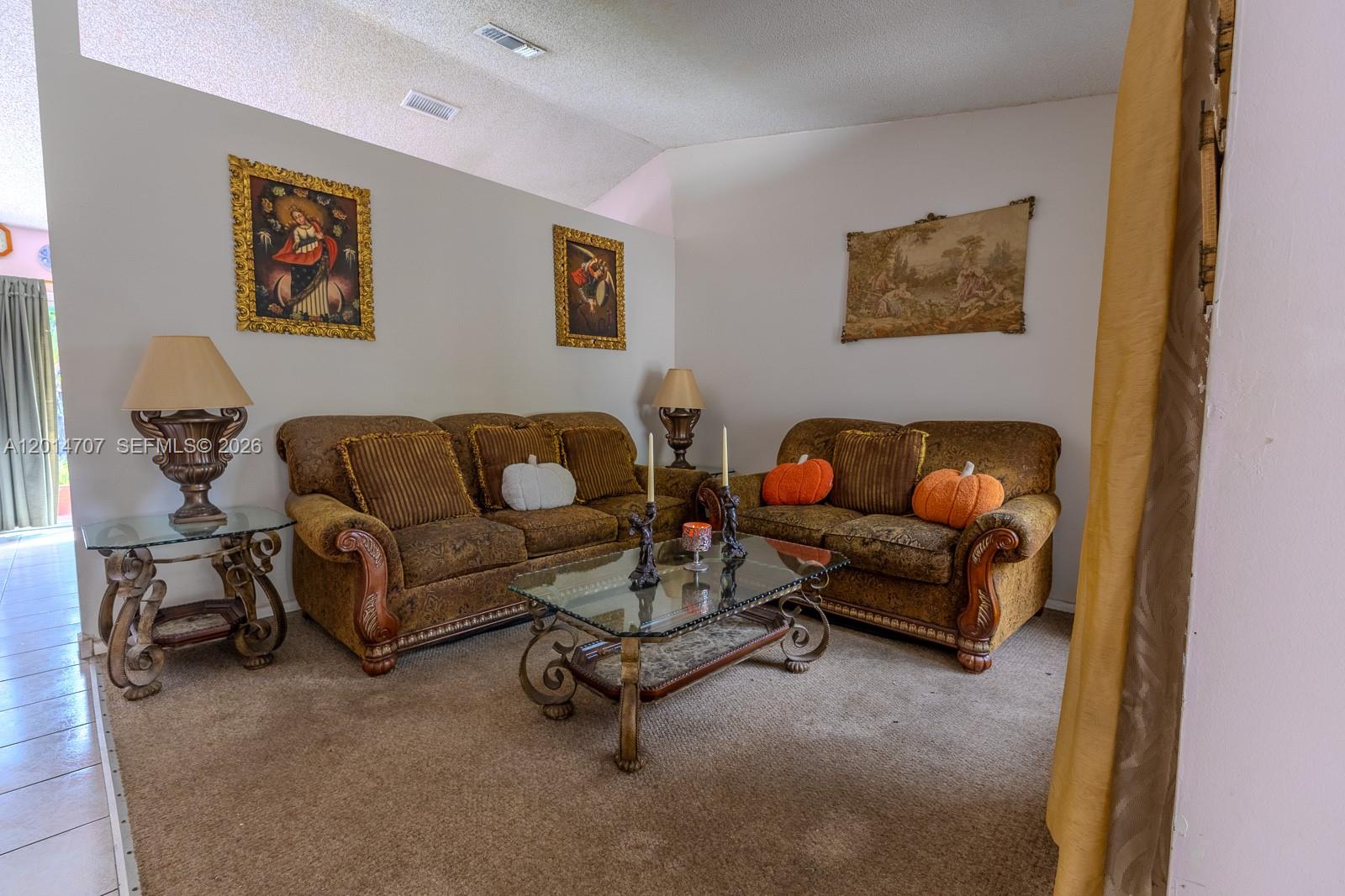 A living room features two brown patterned sofas, a glass coffee table, and wall art — 14452 SW 115th St, Miami FL 33186, MIAMI, FL
