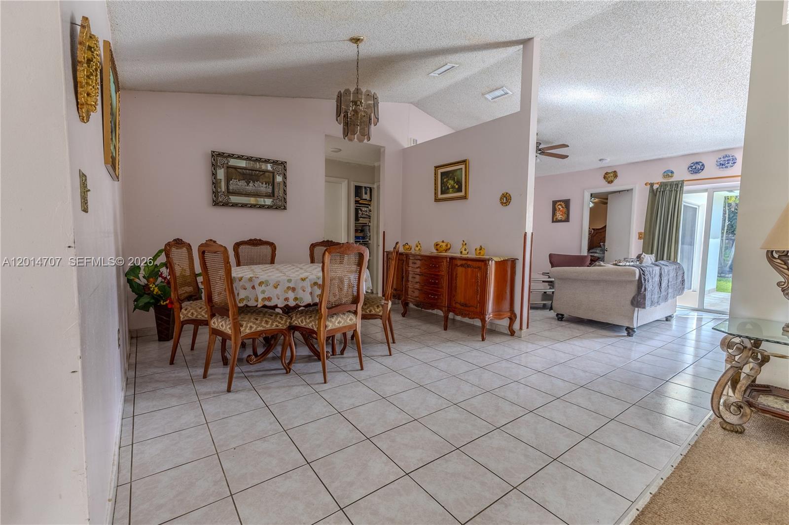 A dining area with a wooden table and chairs sits adjacent to a living room — 14452 SW 115th St, Miami FL 33186, MIAMI, FL