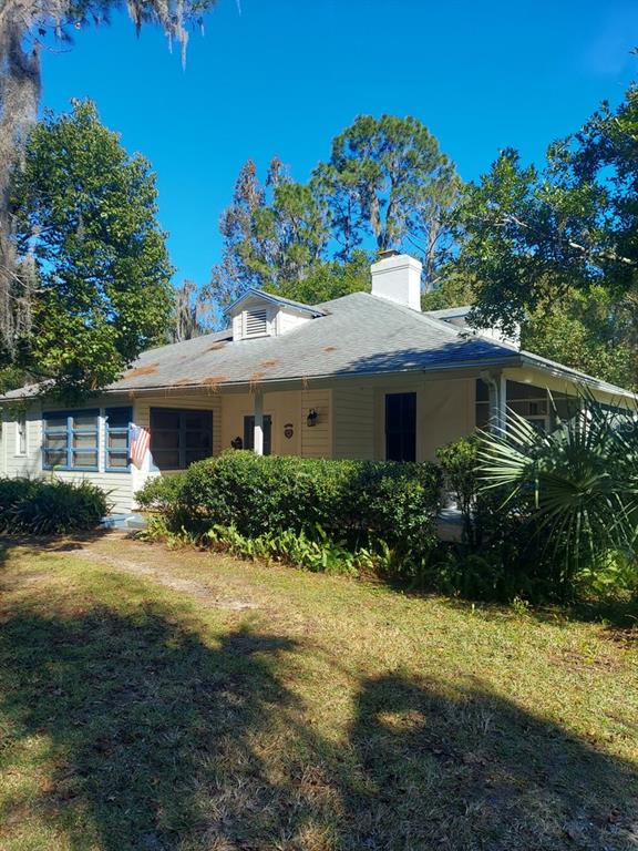 A single-story house with light siding, a white chimney, and a front porch — 251 N BLUE LAKE AVENUE, DELAND, FL