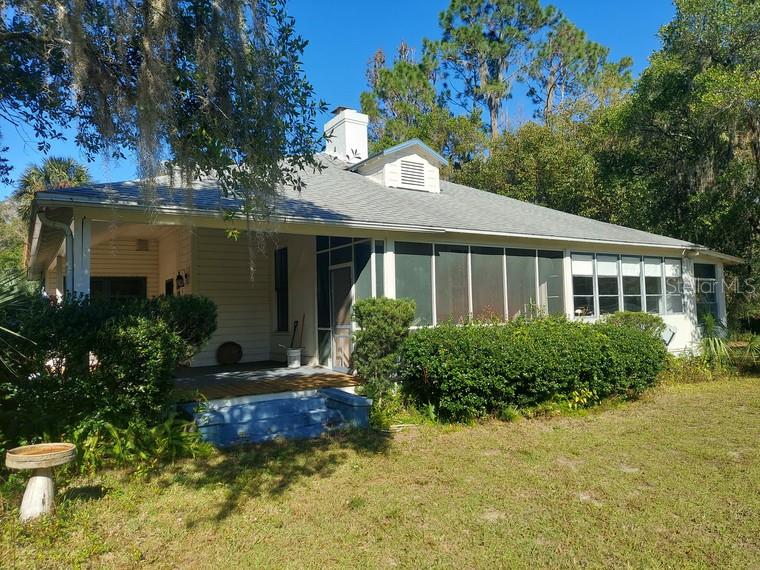 A single-story house with a screened-in porch, a chimney, and a large yard — 251 N BLUE LAKE AVENUE, DELAND, FL