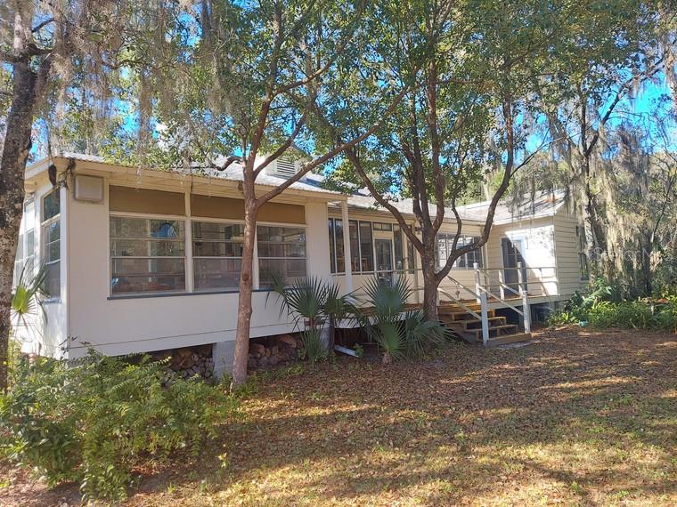 A single-story house with light siding, a metal roof, and a raised wooden deck — 251 N BLUE LAKE AVENUE, DELAND, FL