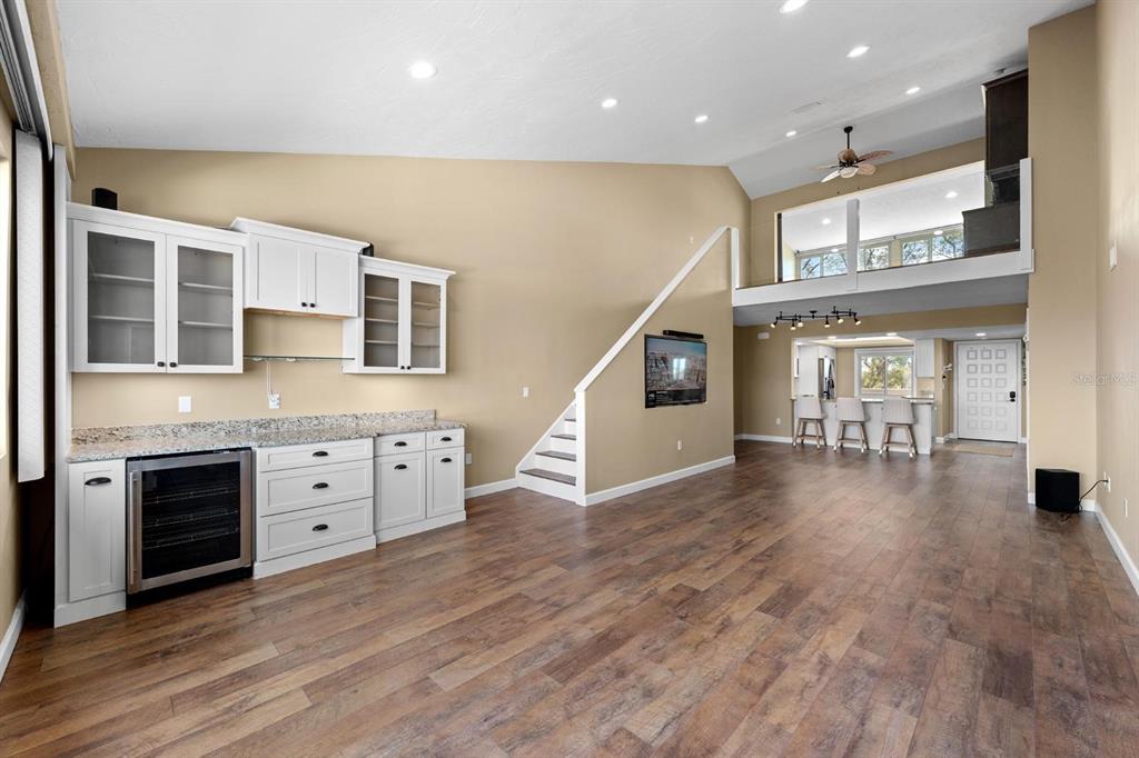 A living room with a wet bar, wood-look flooring, and a loft overlooking the space — 9604 CORTEZ ROAD W UNIT 136, BRADENTON, FL