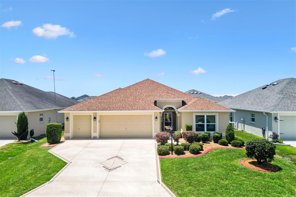 A single-story suburban house with a three-car garage and a landscaped front yard — 4348 TUSCALOOSA PATH, THE VILLAGES, FL