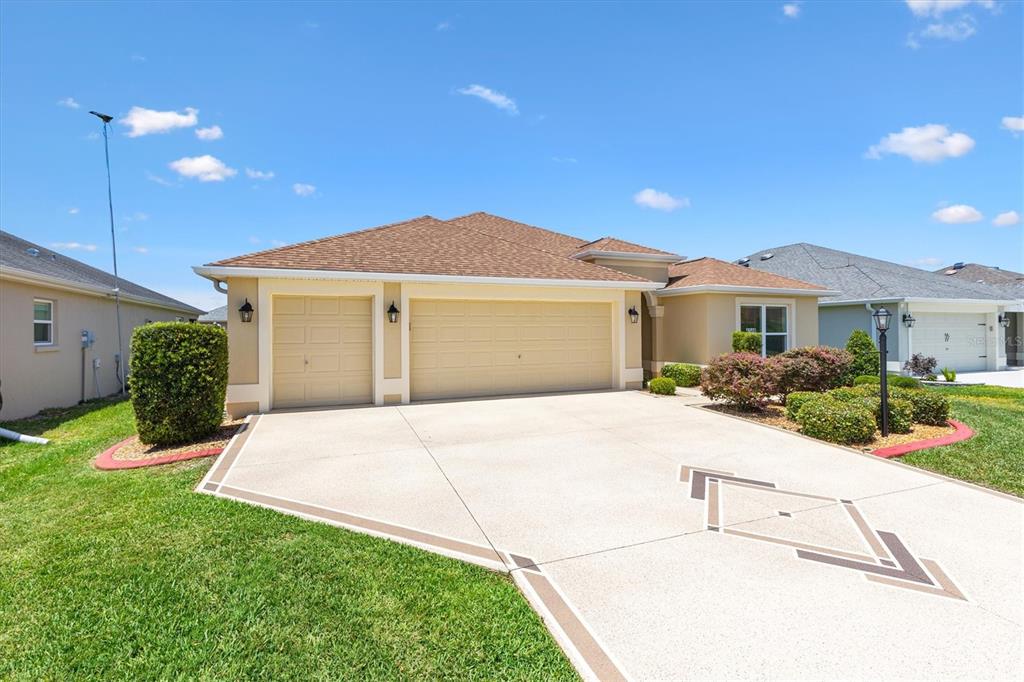 A beige single-story house with a three-car garage and a decorative concrete driveway — 4348 TUSCALOOSA PATH, THE VILLAGES, FL