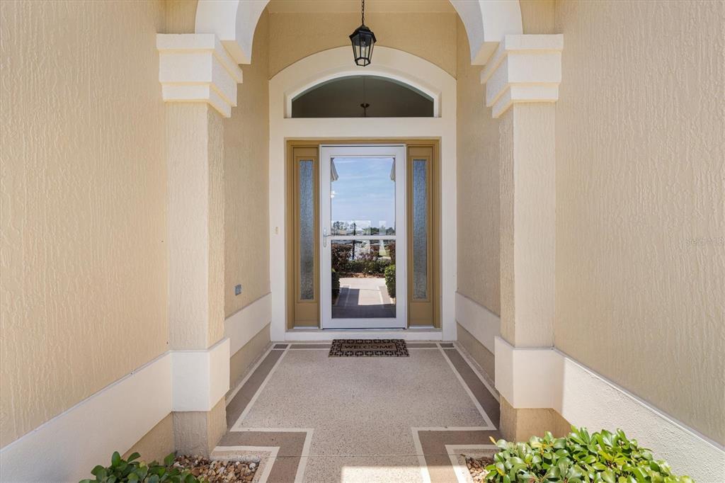 An open two-car garage features a finished epoxy floor, white walls, and a side entry door — 4348 TUSCALOOSA PATH, THE VILLAGES, FL