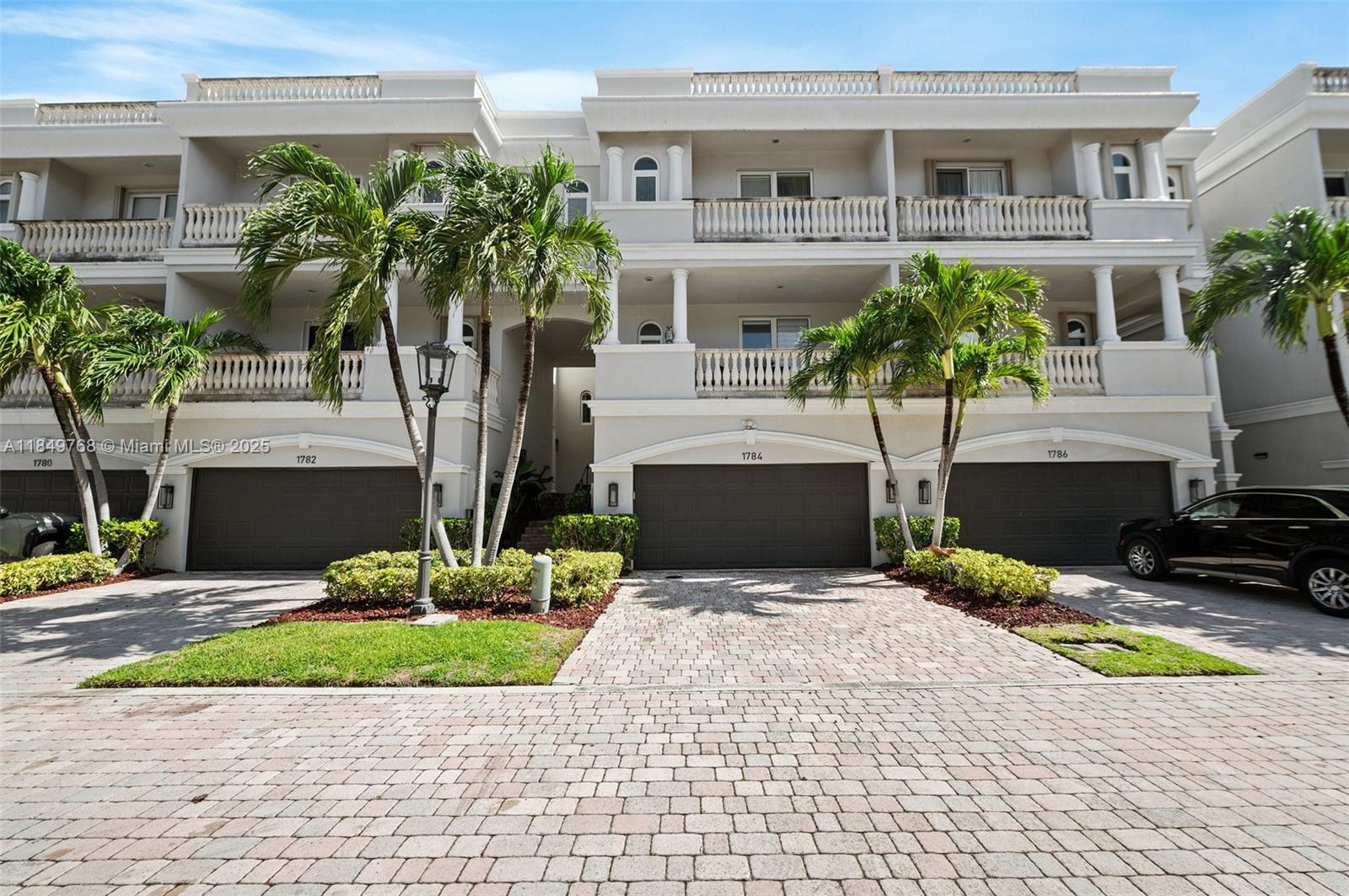 A multi-story residential building features beige stucco facades, arched garage doors, and palm trees — 1784 Bay Dr # 1784, Pompano Beach FL 33062, POMPANO BEACH, FL