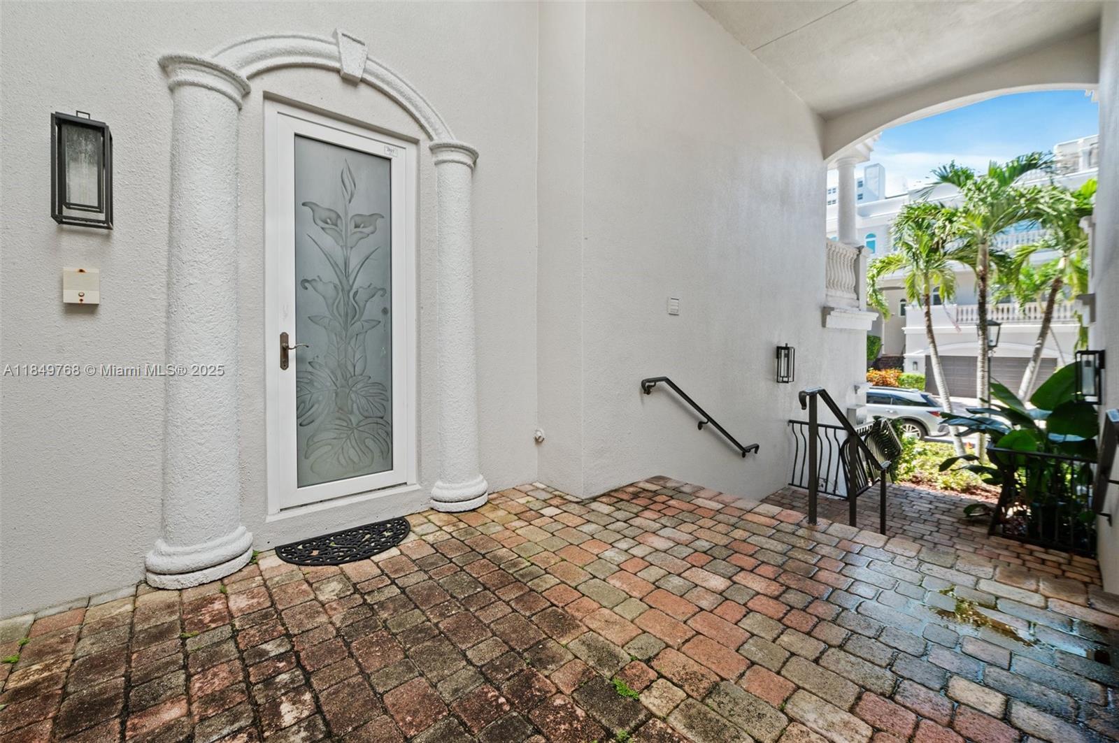 A white door with etched glass sits on a brick patio next to outdoor stairs — 1784 Bay Dr # 1784, Pompano Beach FL 33062, POMPANO BEACH, FL