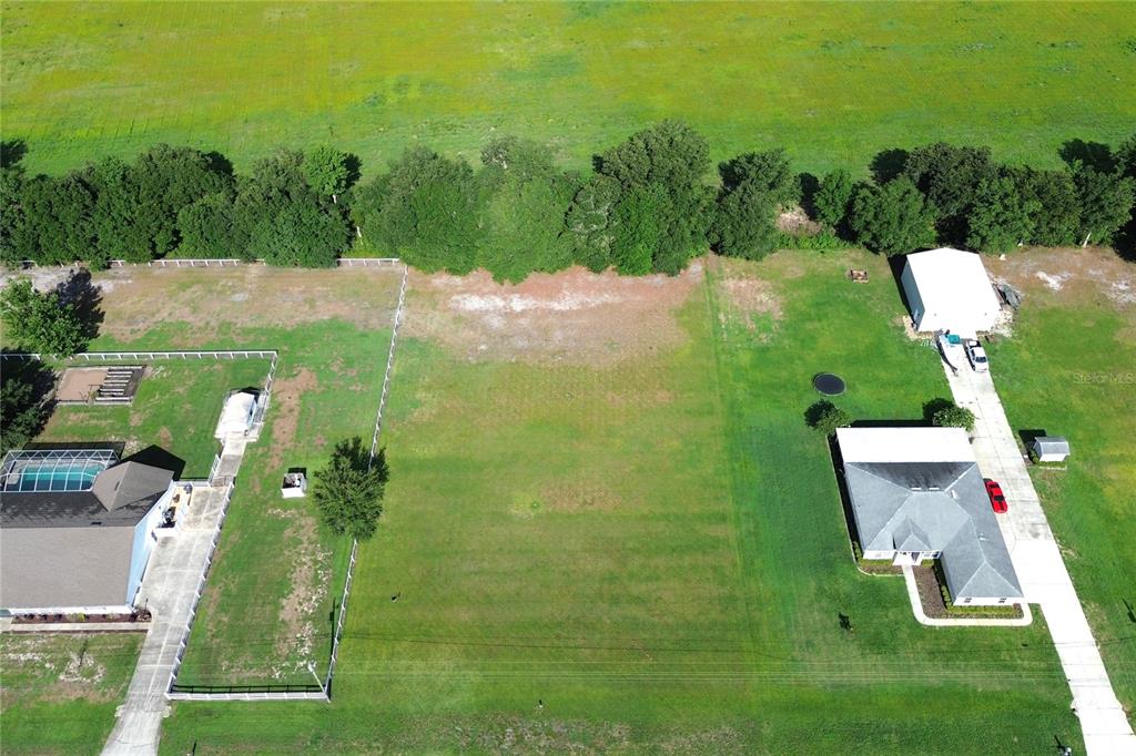 An aerial view shows a vacant residential lot situated between two houses with fenced yards — 14718 EVANS RANCH RD, LAKELAND, FL