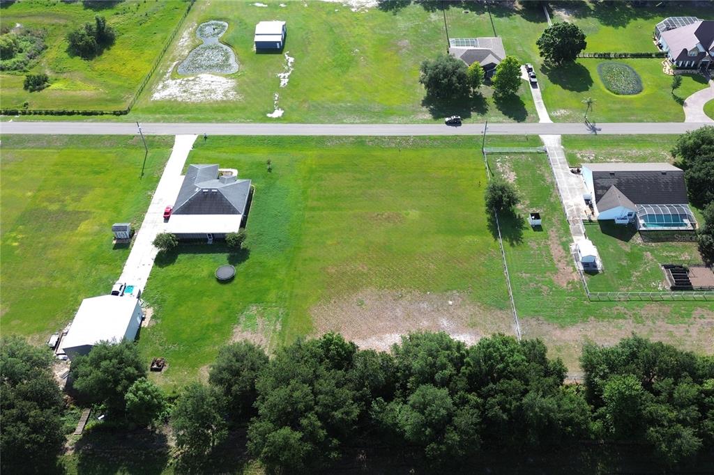 An aerial view shows a vacant residential lot situated between two houses with driveways — 14718 EVANS RANCH RD, LAKELAND, FL