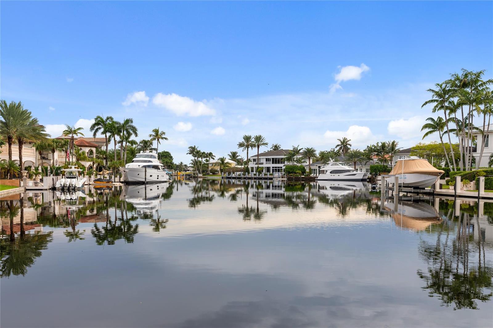 A canal view features luxury yachts docked at private homes surrounded by palm trees — 3211 NE 27th Avenue, Lighthouse Point FL 33064, LIGHTHOUSE POINT, FL