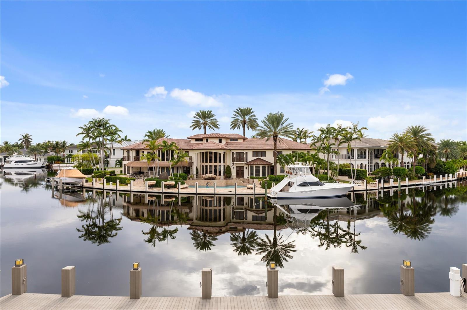 A large waterfront mansion with a pool and docked boats sits along a canal — 3211 NE 27th Avenue, Lighthouse Point FL 33064, LIGHTHOUSE POINT, FL