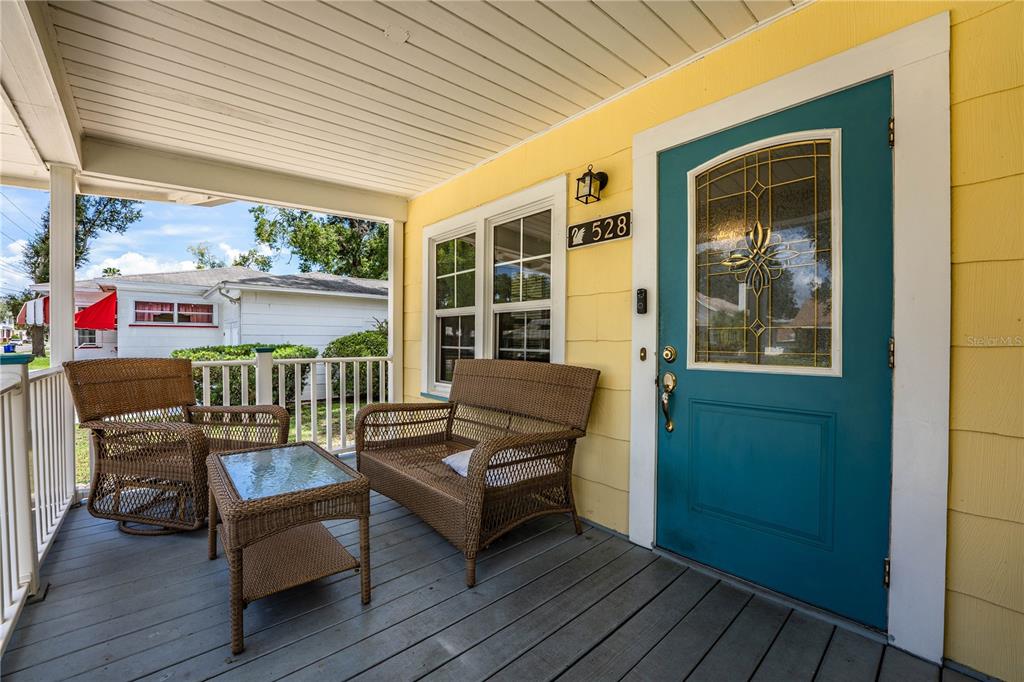 A covered front porch features wicker furniture, a teal door, and yellow siding — 528 S INGRAHAM AVENUE, LAKELAND, FL
