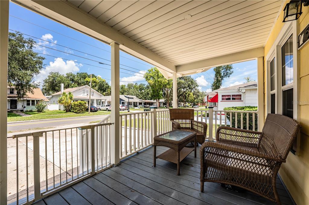 A covered front porch features wicker furniture, a white railing, and a view of the street — 528 S INGRAHAM AVENUE, LAKELAND, FL