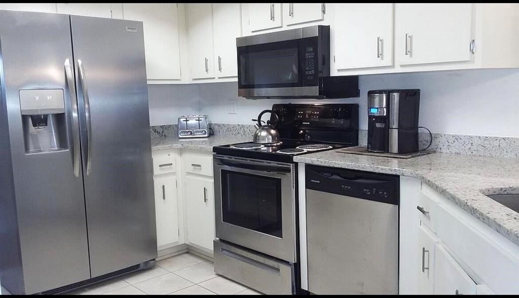 A kitchen features stainless steel appliances, white cabinets, and granite countertops — 8532 SW 109TH LANE ROAD, OCALA, FL