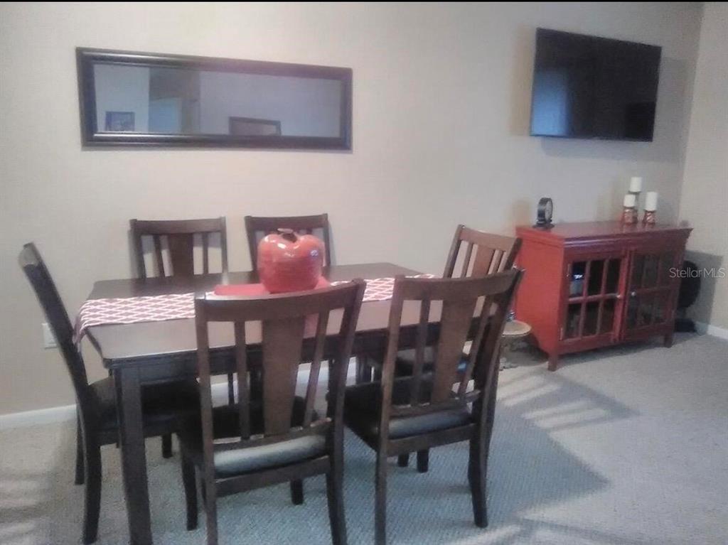 A dining room features a dark wood table with four chairs and a red cabinet — 8532 SW 109TH LANE ROAD, OCALA, FL