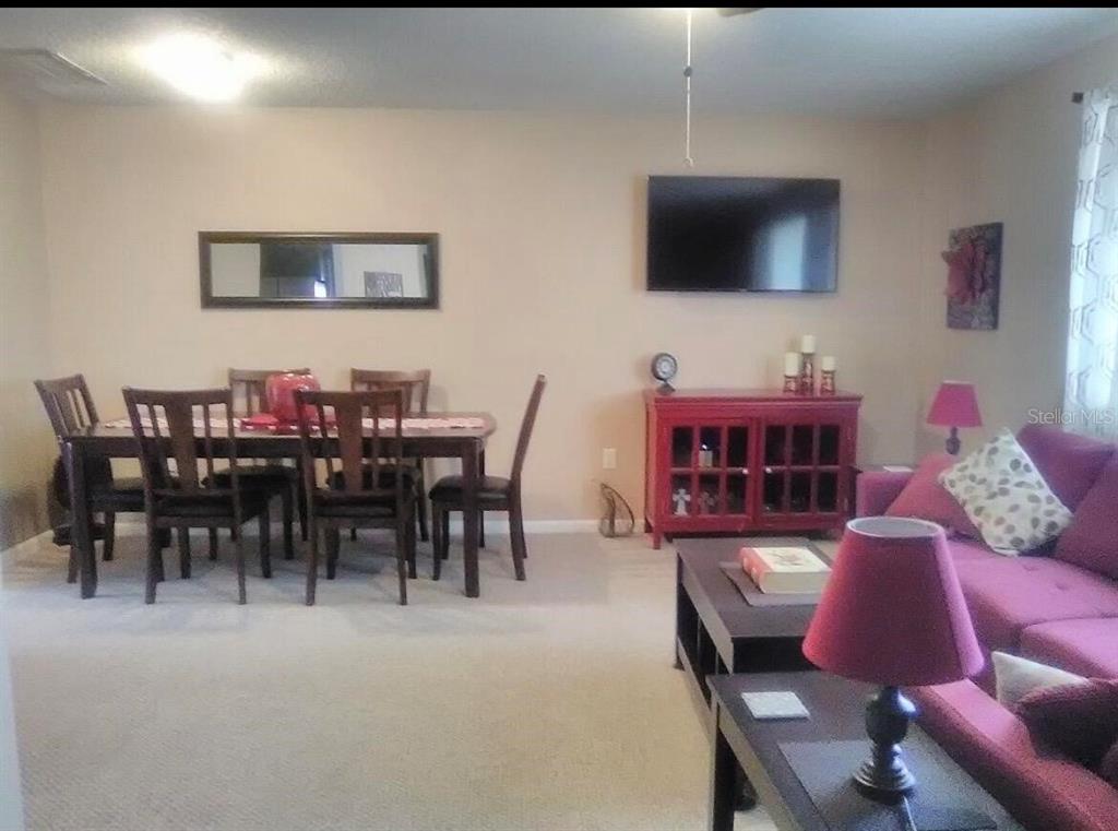A dining area with a wooden table and chairs sits beside a living room area — 8532 SW 109TH LANE ROAD, OCALA, FL