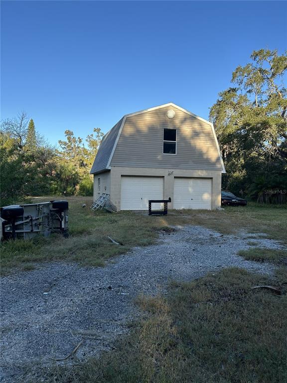 A two-story detached garage with two white doors and a gambrel roof — 14428 GUAVA STREET, HUDSON, FL