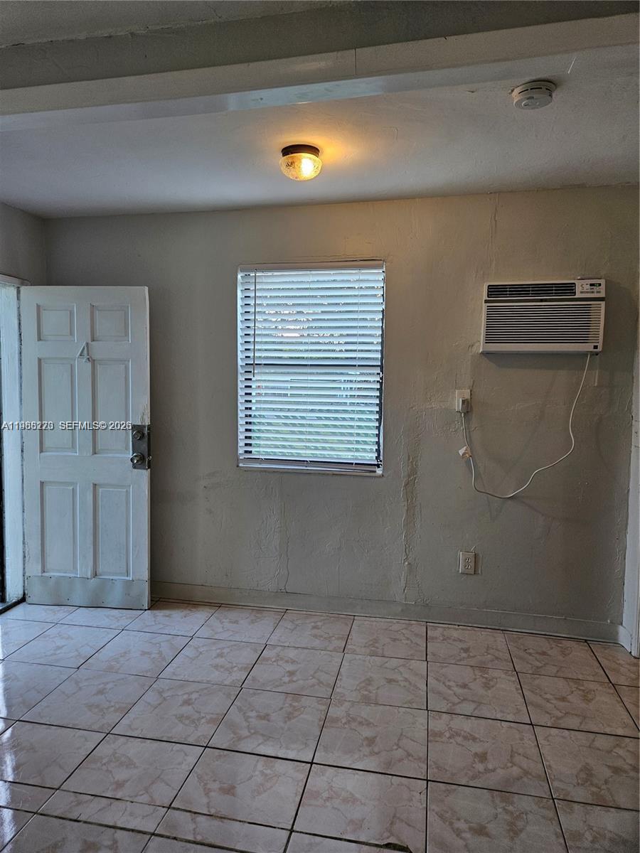 A room with tiled floors, a white door, a window with blinds, and a wall-mounted AC — 1437 NE 110th Ter # 4, Miami FL 33161, MIAMI, FL