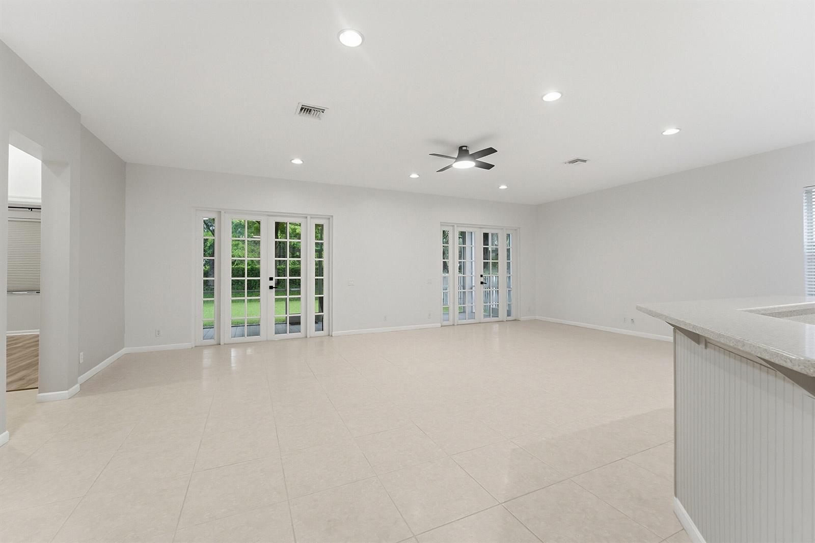 A spacious, light-filled living room features white walls, tile flooring, recessed lighting, and glass doors — 970 Tulip Circle, Weston FL 33327, WESTON, FL