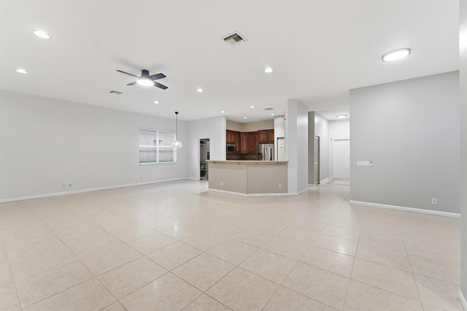 An open-concept living area features light tile flooring, a ceiling fan, and a kitchen island — 970 Tulip Circle, Weston FL 33327, WESTON, FL