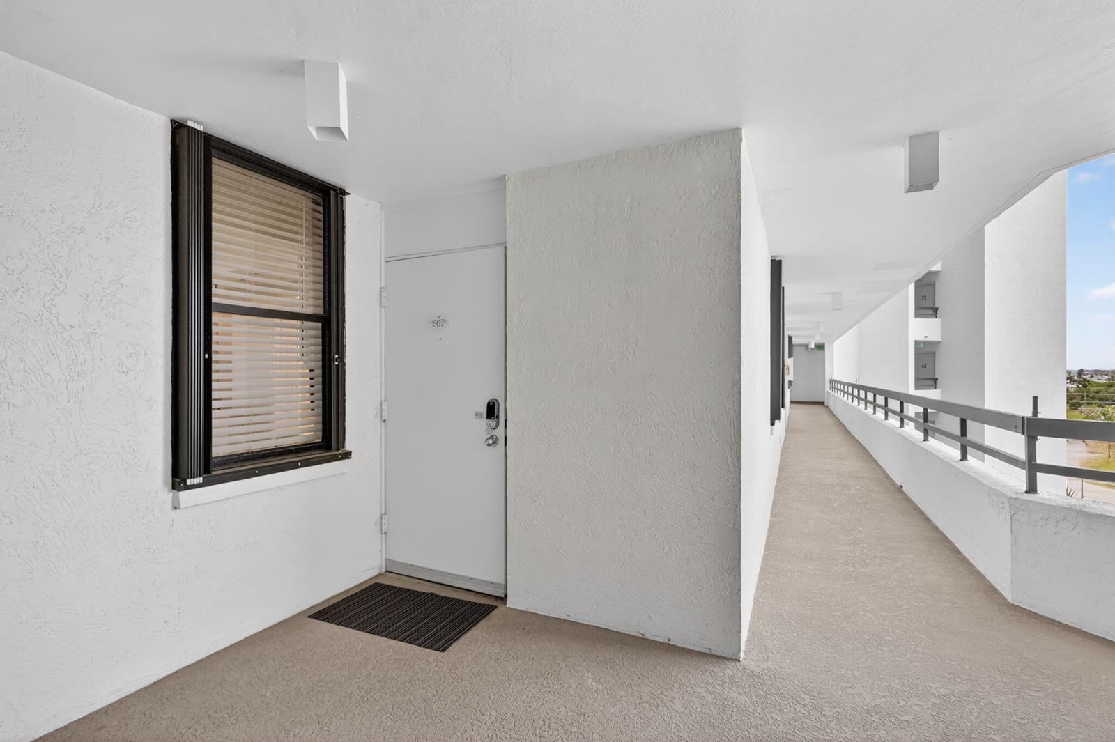 An exterior hallway features a white apartment door numbered 507 with a window nearby — 9650 S Ocean Drive # 507, Jensen Beach FL 34957, JENSEN BEACH, FL