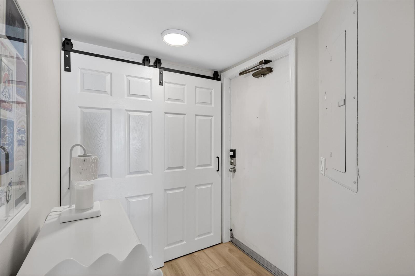 An entryway features a white barn door, a standard entry door, and a white console table — 9650 S Ocean Drive # 507, Jensen Beach FL 34957, JENSEN BEACH, FL