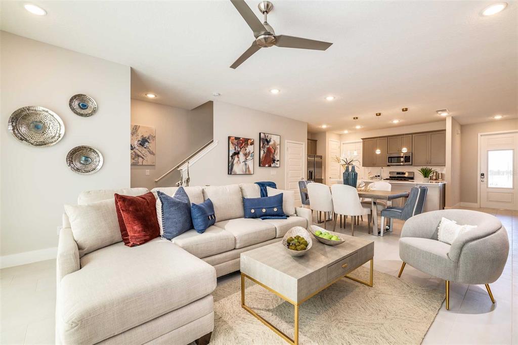 A living room with a sectional sofa, coffee table, and open kitchen in the background — 7920 SPECTRUM DRIVE, KISSIMMEE, FL