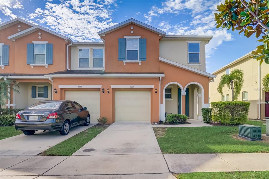 A two-story townhouse with an orange stucco exterior, two garages, and a blue-trimmed window — 5126 ADELAIDE DRIVE, KISSIMMEE, FL