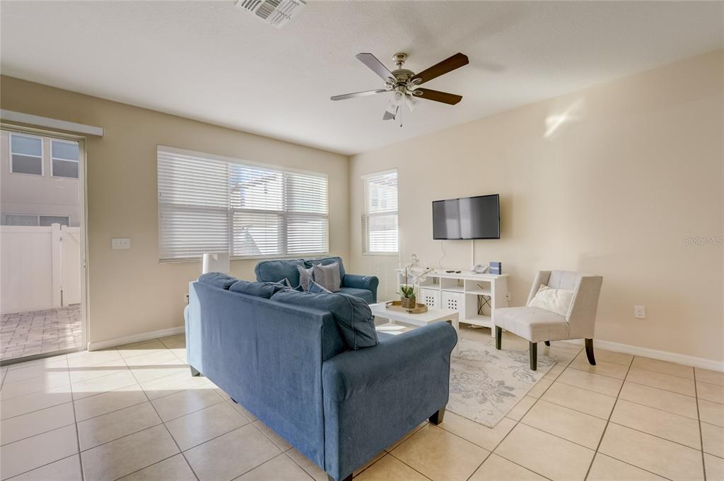 A living room features a blue sofa, a white media console, and tile flooring — 5126 ADELAIDE DRIVE, KISSIMMEE, FL